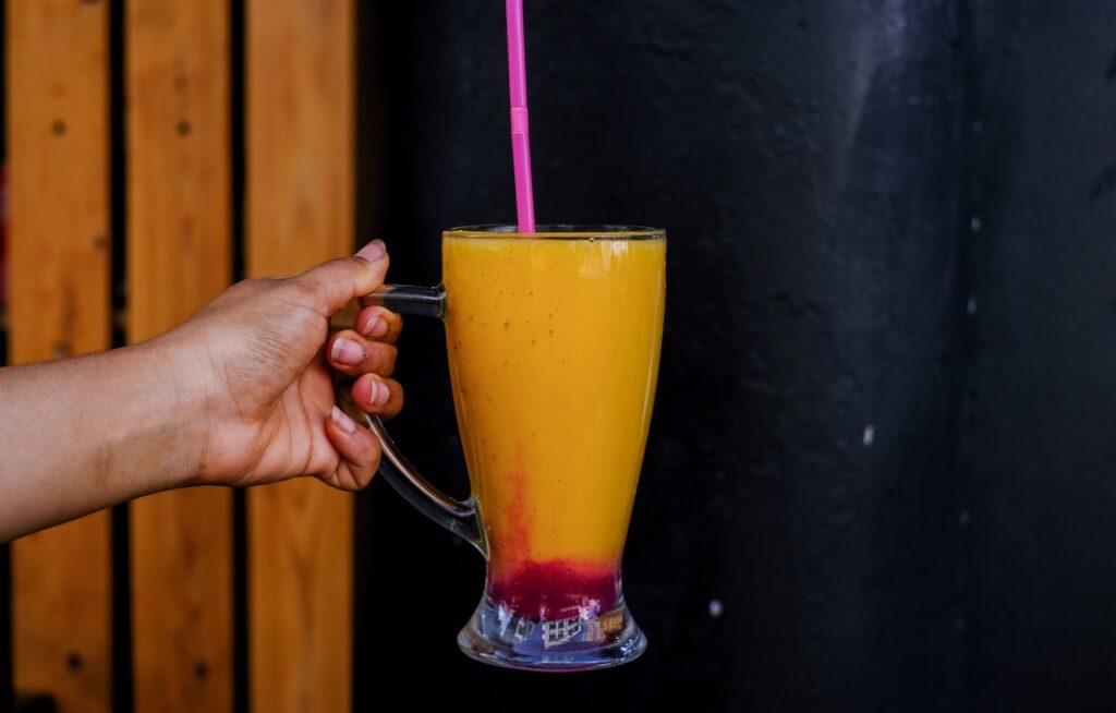 Woman's hand holding a glass of orange and red juice